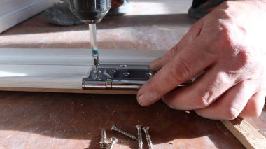 Bir tornavida kullanarak kapı çerçeve yapısının demirine bağlanan bir metal deliğe kendi kendine dokunan vida vidaları yakın çekim çalışan bir matkap ve çerçeve montaj parçaları olarak vida