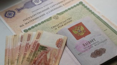 Rusya Federasyonu vatandaşının pasaportu, bir tomar para ve doğum belgesi ve doğum sermaye hakkı içeren bir kompozisyon.
