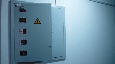 Apartmanın girişindeki elektrik panelinin kapısı açık. Yüksek voltaj tehlikesi ve saydam apartman dairesi elektrik sayaçları var.