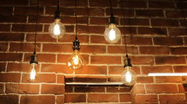 Kablolarda asılı lamba formunda fenerler dokulu tuğla bir duvarın arka planında, odanın eski moda tarzı, kapalı alanda yanan lambalar.