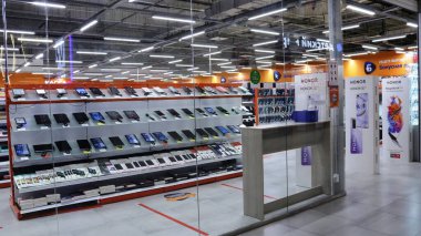 Maikop, Adygea Cumhuriyeti, Rusya - 15 Şubat 2021: Terk edilmiş bir elektronik eşya ve ev aletleri mağazası, parlak turuncu bir tasarım, cam girişi ve serili düz rafları var.