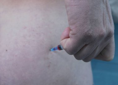 Bir adam kendini sırtının altındaki bir kasın içine enjekte eder. Yakın çekimde kırmızı bir sıvı enjekte eder. İnsan vücuduna kas yoluyla sıvı bir madde enjekte eder.