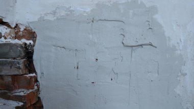 Duvar nemli, düz olmayan bir yüzeye sahip, odanın duvarındaki macunun harç, çimento rengi ve pürüzsüz dokusu, kırmızı tuğlalar ve gri duvarların birleştiği boş bir yapı alanı.