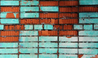 Turkuaz ve terasotta renklerinin birleşiminden oluşan parlak bir tuğla, zaman tarafından yok edilmiş, harap olmuş tuğla duvarın eşsiz bir grafik arka planı, mavi lekeli eski bir cephenin bir parçası.