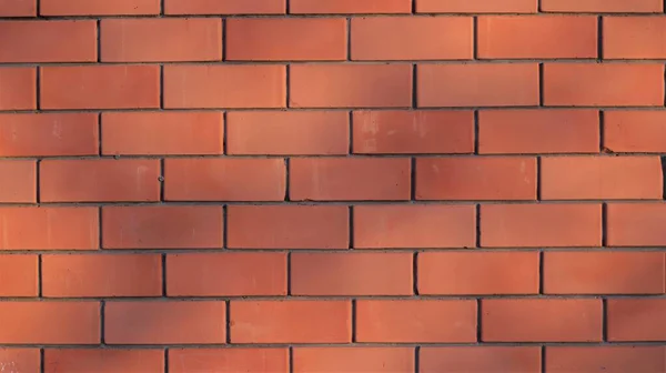 sunny bright orange brick wall with spots of shadows over a ribbed surface, textured empty masonry background with play of sunlight in space, brickwork graphic resource for design backgrounds