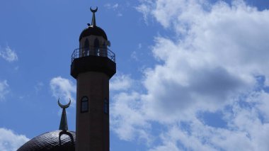 Müslümanların inancının sembolü olarak parlayan beyaz ve mavi gökyüzünün arka planında hilal şeklinde İslami bir cami kubbesi ve bir kubbe.