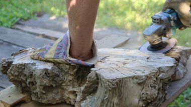 Ağaç gövdesini testereyle kesmenin tek bir parçası kumaş eldivenli bir işleyici tarafından işleniyor. Öğütücü kullanarak temiz havadaki ahşap maddeyi açığa çıkarıyor.
