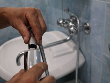 Duş hortumunu kapat ve bağlantı kur. Bulanık banyo arka planında yeni tesisat kurulumu. Ev tesisatı işi.