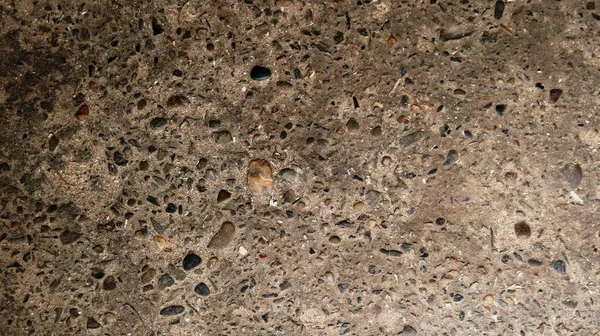 solid background of small pebbles frozen in the structure of concrete, cement backdrop interspersed with gravel, stone texture space of gray-brown shades