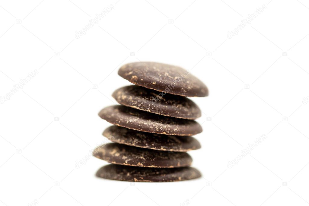 A close up of a pile of dark chocolate buttons, with a shallow depth of field