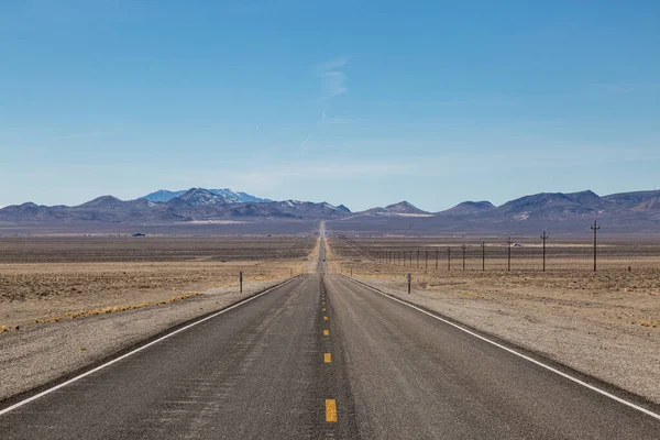 沿着一条穿过内华达沙漠的笔直的长路往下看 — 图库照片
