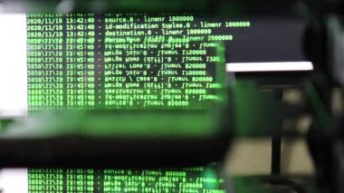 Siyah ekranda hareket eden yeşil bilgisayar yazılım kodu cama yansıyor. Raf sunucu tabanı, dinamik metin çalışan ve pc ekranında akan soyut bilgisayar hack 'leme işlemi.
