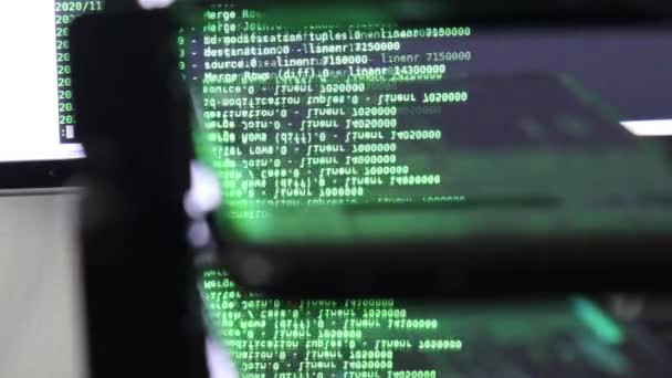 ブラックモニター上の緑色のコンピュータソフトウェアコードは ガラスに反映されます 概要ラックサーバベースで処理中のコンピュータのハッキング 動的テキストの実行とPc画面上で流れる — ストック動画