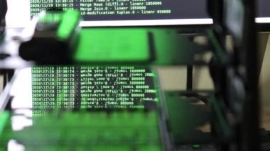 Siyah ekranda hareket eden yeşil bilgisayar yazılım kodu cama yansıyor. Raf sunucu tabanı, dinamik metin çalışan ve pc ekranında akan soyut bilgisayar hack 'leme işlemi.
