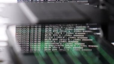 Siyah ekranda hareket eden beyaz bilgisayar yazılım kodu cama yansıyor. Raf sunucu tabanı, dinamik metin çalışan ve pc ekranında akan soyut bilgisayar hack 'leme işlemi.