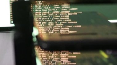 Siyah ekranda hareket eden turuncu bilgisayar yazılım kodu cama yansıyor. Raf sunucu tabanı, dinamik metin çalışan ve pc ekranında akan soyut bilgisayar hack 'leme işlemi.
