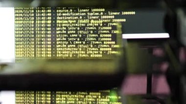 Siyah ekranda hareket eden sarı bilgisayar yazılım kodu cama yansıyor. Raf sunucu tabanı, dinamik metin çalışan ve pc ekranında akan soyut bilgisayar hack 'leme işlemi.