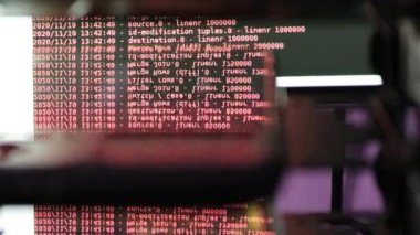 Siyah ekranda hareket eden kırmızı bilgisayar yazılım kodu cama yansıyor. Raf sunucu tabanı, dinamik metin çalışan ve pc ekranında akan soyut bilgisayar hack 'leme işlemi.