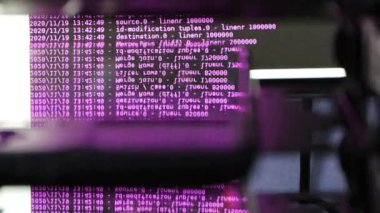 Siyah ekranda hareket eden mor bilgisayar yazılım kodu cama yansıyor. Raf sunucu tabanı, dinamik metin çalışan ve pc ekranında akan soyut bilgisayar hack 'leme işlemi.