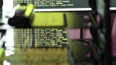 Siyah ekranda hareket eden sarı bilgisayar yazılım kodu cama yansıyor. Raf sunucu tabanı, dinamik metin çalışan ve pc ekranında akan soyut bilgisayar hack 'leme işlemi.