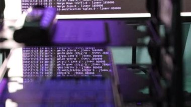 Siyah ekranda hareket eden mor bilgisayar yazılım kodu cama yansıyor. Raf sunucu tabanı, dinamik metin çalışan ve pc ekranında akan soyut bilgisayar hack 'leme işlemi.