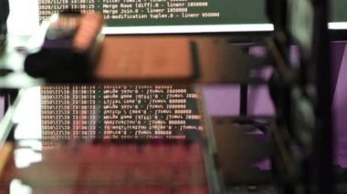 Siyah ekranda hareket eden turuncu bilgisayar yazılım kodu cama yansıyor. Raf sunucu tabanı, dinamik metin çalışan ve pc ekranında akan soyut bilgisayar hack 'leme işlemi.
