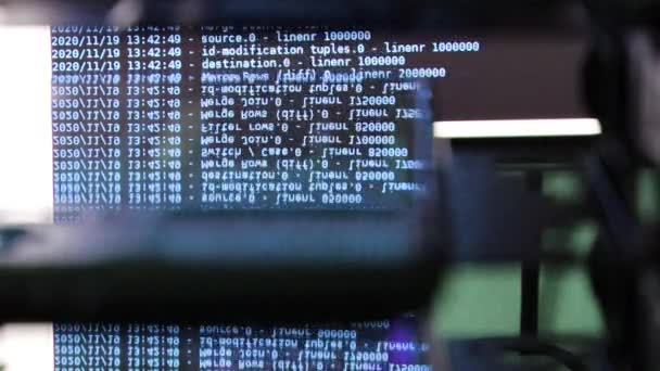 ブラックモニター上で動く青いコンピュータソフトウェアコードはガラスに反射しています 概要ラックサーバベースで処理中のコンピュータのハッキング 動的テキストの実行とPc画面上で流れる — ストック動画