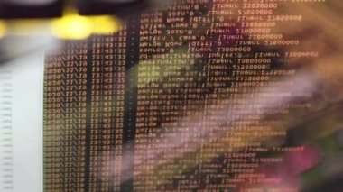 Siyah ekranda hareket eden turuncu bilgisayar yazılım kodu cama yansıyor. Raf sunucu tabanı, dinamik metin çalışan ve pc ekranında akan soyut bilgisayar hack 'leme işlemi.
