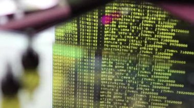 Siyah ekranda hareket eden sarı bilgisayar yazılım kodu cama yansıyor. Raf sunucu tabanı, dinamik metin çalışan ve pc ekranında akan soyut bilgisayar hack 'leme işlemi.