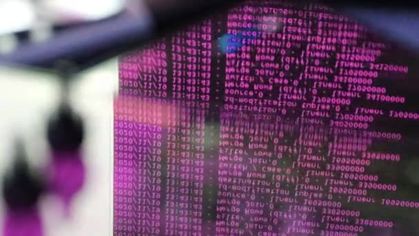 ブラックモニター上で動くピンクのコンピュータソフトウェアコードはガラスに反映されます 概要ラックサーバベースで処理中のコンピュータのハッキング 動的テキストの実行とPc画面上で流れる — ストック動画