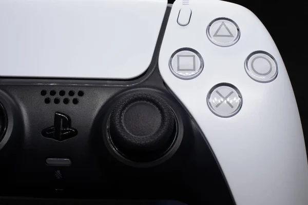 PS5 oyun sahası ışıklar ve gölgelerle kapanıyor. Logo ayrıntıları ve makro düğmesi olan siyah ve beyaz playstation 5 denetleyici.