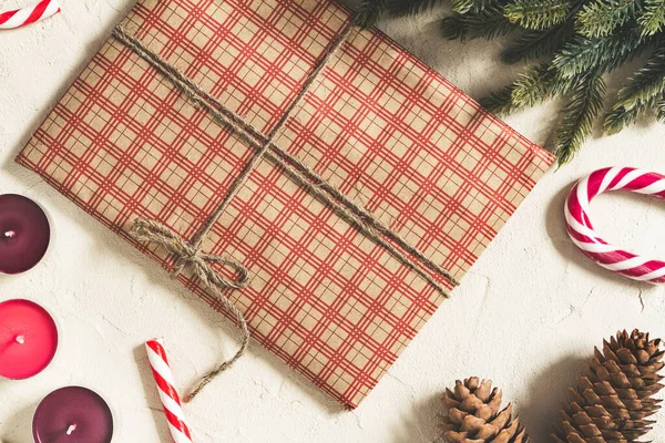 Kareli el sanatları kağıdına sarılı bir Noel hediyesi. Üzerinde mumlar ve süslemeler var.
