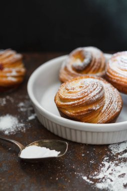 Beyaz bir tabakta şeker tozuyla kaplı fırında pişmiş kabuklar, yemek arkaplanı.