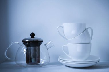 Sütlü ve kavanozlu bir masada çay içmek için birkaç beyaz fincan.