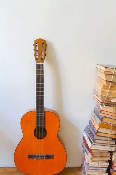 オレンジのアコースティック ギターとほこりだらけの古い本の山. — ストック写真