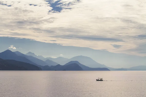 Deniz, dağlar ve balıkçı teknesi.