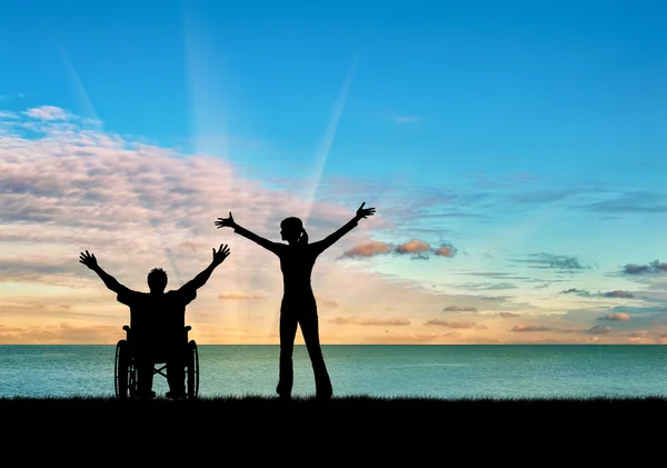 Sziluettjét boldog fogyatékkal élő személy és a gyámja — Stock Fotó