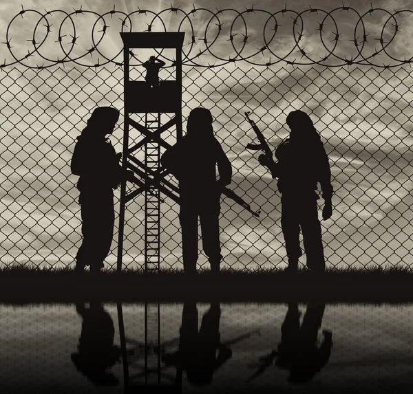 Silhouette terrorists near the border fence — Stock Photo, Image