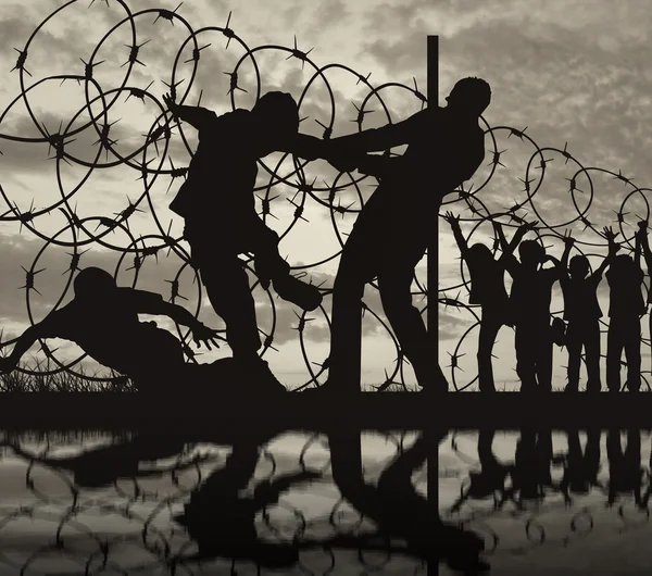 Silhueta de refugiados e arame farpado — Fotografia de Stock