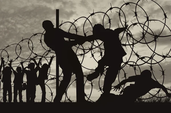 Silhueta de refugiados e arame farpado — Fotografia de Stock