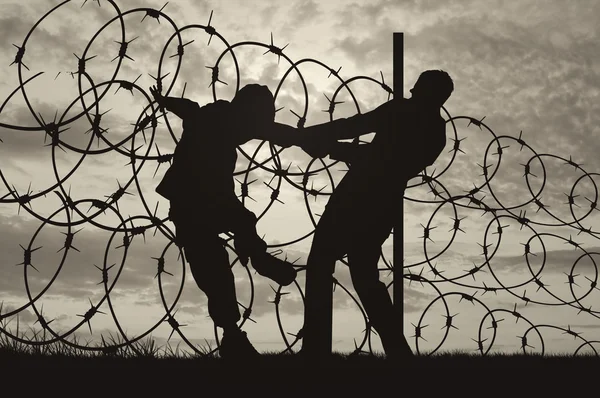 Silhueta de refugiados e arame farpado — Fotografia de Stock