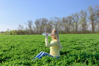  Genç kadın rahatlatıcı bir plastik şişe suyu içer