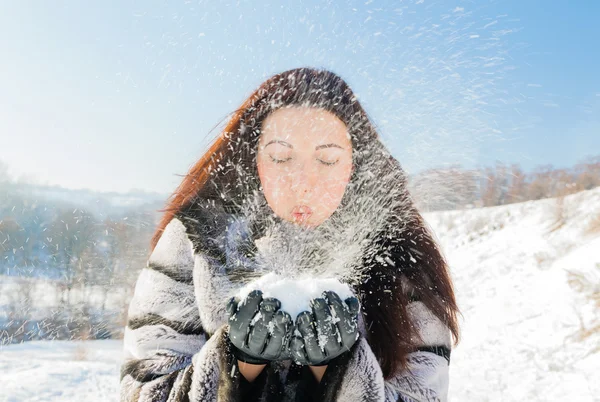 Woman blowing in the snow in her hands — Stock Photo, Image