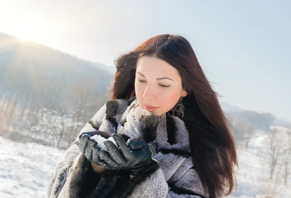 Kobieta dmuchanie w śniegu w jej ręce — Zdjęcie stockowe
