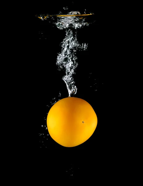 Gele tomaat vallen in het water — Stockfoto