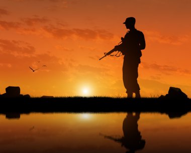 Bir terörist Nehri yakınında günbatımında bir silahla silüeti