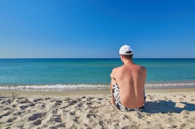 Sahilde oturan genç adam