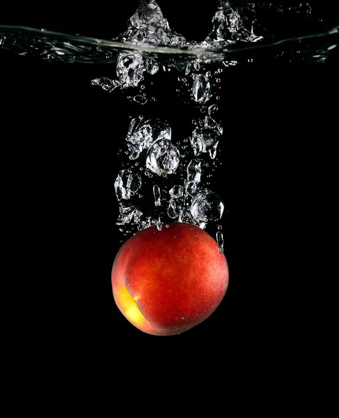 Peach falling into the water — Stock Photo, Image