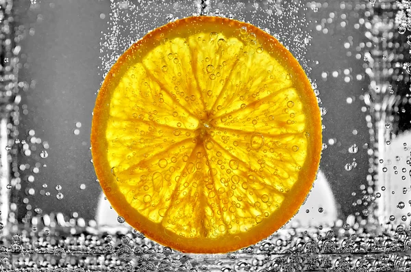 Saftig bit av orange frukt i vatten — Stockfoto