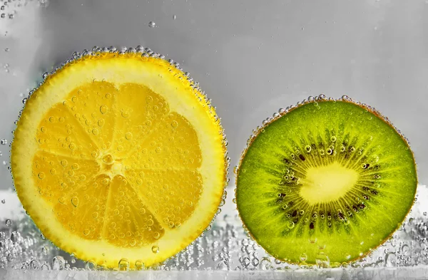 Rodajas de limón y kiwi en agua —  Fotos de Stock